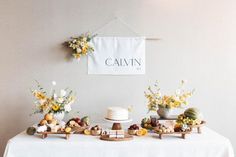 a table topped with cakes and desserts next to a wall hanging on the wall