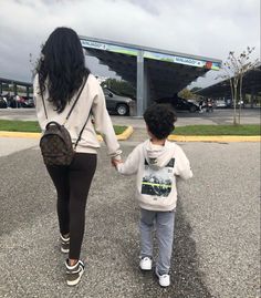 a woman holding the hand of a young boy who is walking in front of an airport