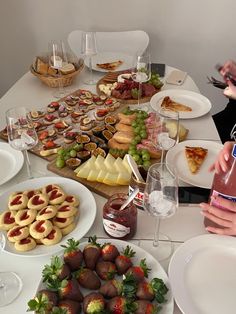 a table full of food and desserts with people sitting at the table to eat