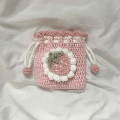 a pink crocheted purse with a green leaf on the front and white trim