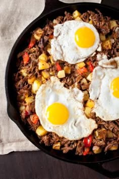 two fried eggs on top of some meat in a skillet