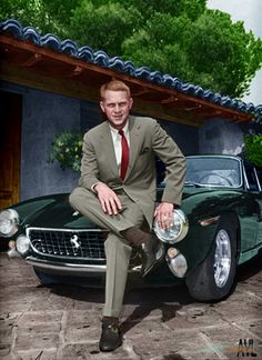 a man in a suit and tie sitting on top of a green vintage sports car