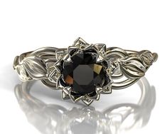 a black diamond ring with leaves on the sides and a center stone in the middle