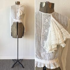 "Vintage Victorian white cotton net and lace blouse with long sleeves and a very large flouncy ruffle coming off a crochet placard down the front. The net has pintuck creating a ribbon effect The sleeves each have two functioning buttons and a small trim of lace. The waist is gathered to create a ruffle around and is backed with ribbon. The whole blouse is lined with net. The blouse buttons down the back with a covered placard to hide the buttons. Single hook and eye at waist. Simple crew neck. White Lace Top With Ruffles, Lace Top With Ruffles For Daywear, Victorian White Long Sleeve Blouse, White Victorian Long Sleeve Blouse, Fitted Cotton Lace Top With Ruffles, White Long Sleeve Victorian Top, Long Sleeve Lace Top With Ruffles For Wedding, Wedding Long Sleeve Lace Top With Ruffles, Victorian Ruffle Tops For Daywear