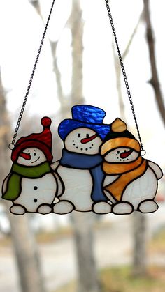 stained-glass-suncatcher-in-the-form-of-three-hugging-snowmen-in-colorful-hats-and-scarves-is-suspended-on-the-window-opposite-the-sun Snowman Stained Glass Patterns, Vitromosaico Ideas, Stained Glass Art Window, Funny Snowmen, Stained Glass Snowman, Unusual Christmas Ornaments, Suncatcher Window, Glass Snowman