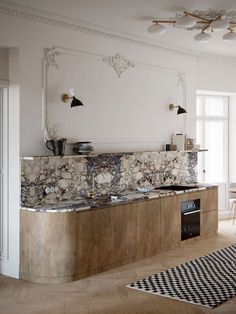 a kitchen with marble counter tops and an oven in the center, next to a dining room table