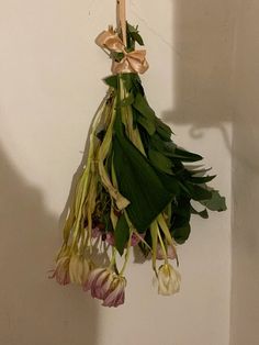 a bunch of flowers hanging from a hook on the wall next to a white wall