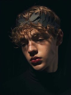 a young man with curly hair wearing a black shirt and a paper crown on his head