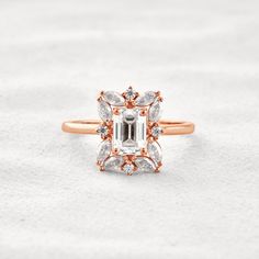 a rose gold ring with an emerald cut diamond surrounded by small white and brown diamonds