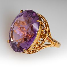 This fantastic vintage cocktail ring is accented with one (1) oval cut natural amethyst that is set into a four-prong setting. The gallery features an openwork design filled with filigree scrolls. The ring measures 20.2mm at the top, rises 11.9mm above the finger, tapering to 2.1mm wide and 0.8mm thick at the base of the shank. It is currently a size 5.75. Oval Purple Amethyst Ring With Filigree, Oval Purple Filigree Amethyst Ring, Purple Oval Amethyst Ring With Filigree, Purple Oval Filigree Rings, Oval Amethyst Ring With Intricate Design, Elegant Purple Amethyst Ring With Filigree, Formal Purple Amethyst Ring With Filigree, Elegant Purple Amethyst Filigree Ring, Vintage Oval Amethyst Ring With Filigree