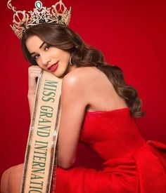 a woman in a red dress is wearing a tiara and posing for the camera