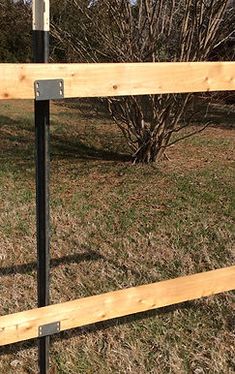 a wooden fence with metal posts in the grass