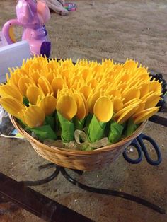 a basket filled with yellow flowers sitting on top of a wooden table next to a pink toy