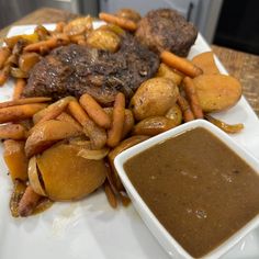 a white plate topped with meat, potatoes and carrots next to gravy