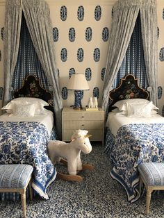 two beds in a room with blue and white decor on the walls, one has a rocking horse