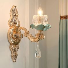 a wall light with a glass shade hanging from it's side next to a curtain