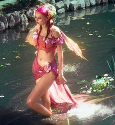 a woman in a pink costume is standing in the water with her hands on her hips