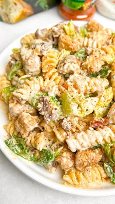 a white plate topped with pasta covered in meat and veggies next to bread