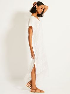 Simple and elegant, the Abira collection features a textured solid and sheer weaving highlighted by delicate shimmering silver dots on a bright white background.This classic caftan features a plunge neckline, short cap sleeves, hand-twisted fringe hem making it the perfect beach cover-up. Hand-woven in Ethiopia, this silhouette is made of soft hand-spun cotton for a light and comfortable feel. GIVING BACK | 5% of all purchases will be donated to the lemlem Foundation. Elegant White V-neck Kaftan, Chic White V-neck Kaftan, Elegant White Kaftan For Daywear, Chic White Kaftan For Beach Cover-up, Chic White Tunic Kaftan, Chic Long White Kaftan, White V-neck Kaftan For Daywear, Elegant White Beach Kaftan, Bright White Background