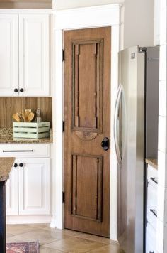 a wooden door in a kitchen next to a refrigerator