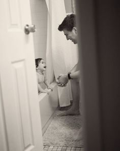 a man is brushing his teeth in the bathroom while a child sits on the toilet