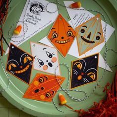 several halloween cards on a green plate with orange and white string hanging from it's sides