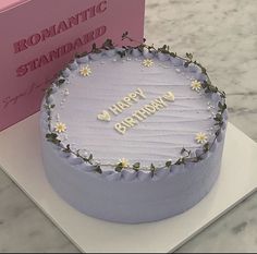 a birthday cake sitting on top of a table next to a pink card and box