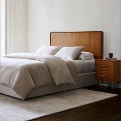 a bed with white linens and pillows in a bedroom next to a large window