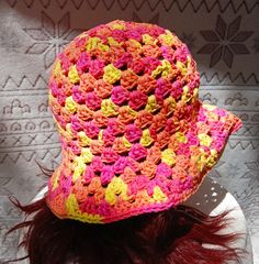 a crocheted hat is sitting on top of a woman's head with long red hair