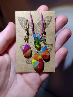 a person holding some kind of earrings in their hand with a butterfly on the back