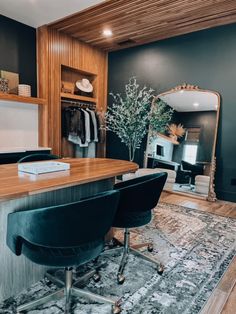 a desk with two chairs and a mirror on the wall above it in a room that has wood paneling