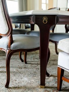 a dining room table with chairs and a rug on the floor in front of it