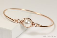 White Pearl Bangle Handmade by Jessica Luu Jewelry ~ Sophisticated ~ Versatile ~ Elegant ~ Perfect for everyday wear, this white pearl bangle adds a touch of casual elegance to every occasion - available in 2 metal choices. MATCHING ITEMS https://www.etsy.com/shop/JessicaLuuJewelry?search_query=white+pearl+wp MATERIALS: ~ 10mm white crystal nacre pearl ~ 14K gold filled wire HOW IT'S MADE: A large pearl is wire wrapped in a herringbone style then attached to a bangle bracelet that has been forme Rose Gold Wire Wrapped Jewelry For Party, Rose Gold Metal Bangle For Wedding, Elegant Wire Wrapped Wedding Bracelets, Rose Gold Bracelet For Bridesmaid Gift, Elegant Adjustable Bangle For Bridesmaid Gift, Adjustable Rose Gold Wire Wrapped Bracelets, Rose Gold Bangle Pearl Bracelet As A Gift, Elegant Adjustable Rose Gold Bracelet, Elegant Rose Gold Bracelets For Bridesmaid Gift