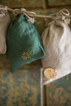 three bags are hanging on the wall with buttons and string attached to them, along with a wooden button