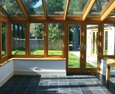 the inside of a house with large windows and tiled flooring, along with wooden benches