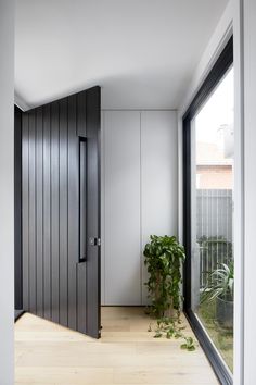 an open door leading into a room with wooden floors and walls, along with a plant in the corner