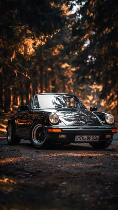 a black sports car parked in the middle of a forest