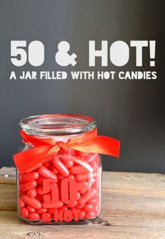 a jar filled with red candies sitting on top of a wooden table next to a sign