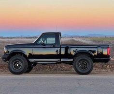 the truck is parked on the side of the road in front of an empty field