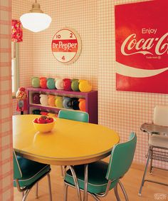 a dining room table with chairs and a coca - cola sign on the wall behind it