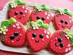 decorated cookies in the shape of strawberries on a tray