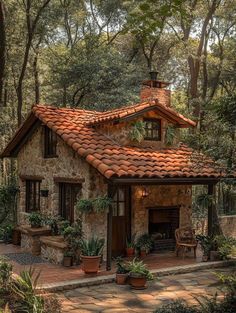 a small stone house with potted plants on the front porch and an open fire place