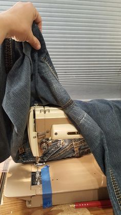 someone using a sewing machine to sew jeans