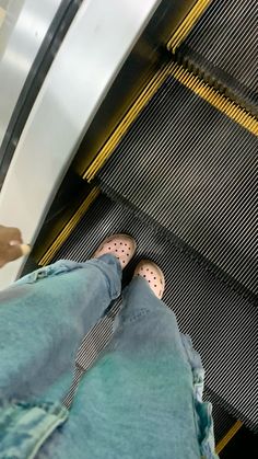 someone is standing on an escalator with their feet in the air and they are wearing polka dot shoes