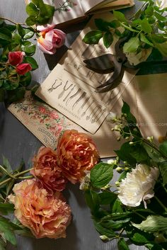 some flowers are laying on top of an open book with scissors and other items around it