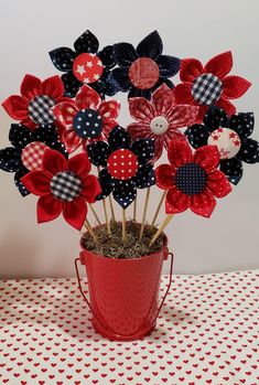 red, white and blue pinwheels in a bucket on top of a table