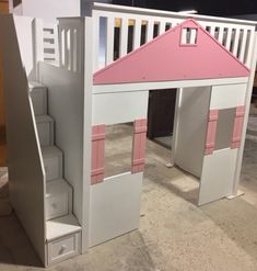 a doll house made out of cardboard with stairs leading up to the roof and pink shutters