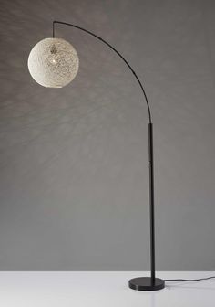 a black and white floor lamp with a round light bulb on it's side