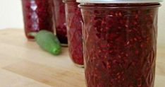 three jars filled with jam sitting on top of a wooden table