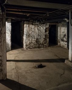 an empty room with exposed pipes and stone walls